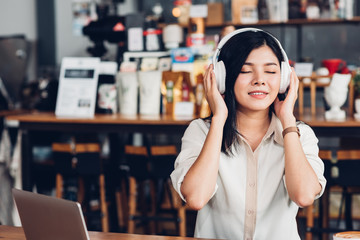 Lifestyle freelance woman he using earphones listening music during working on laptop computer