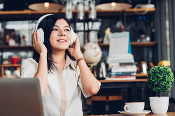 Lifestyle freelance woman he using earphones listening music during working on laptop computer