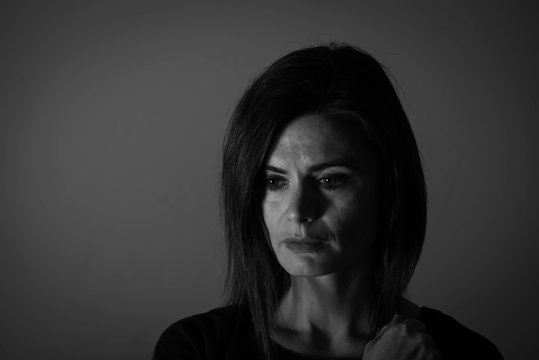 Black and white portrait of a middle age woman looking sad.