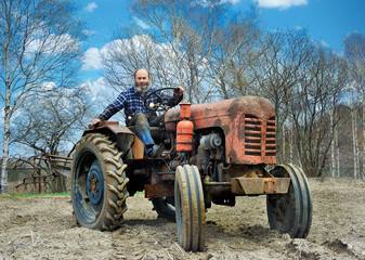 the bearded farmer establishes a plow on a tractor. Tractor on an arable land