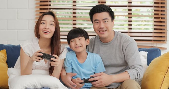 Father and mother playing console game with they son at home. They playing console game with funny emotion together. Lifestyle, Technology and Family concept.