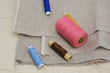 Linen fabrics of different textures and multi-colored threads on the reels. Sewing theme