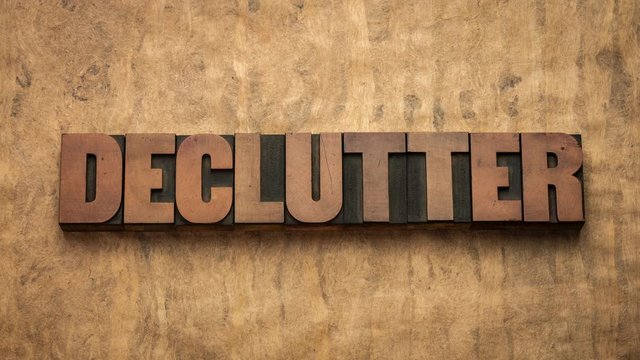 Declutter word, minimalism and simple living concept - stop motion animation with vintage letterpress wood type block against handmade bark paper.