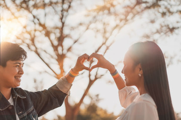 Obraz premium Happy romantic asian lesbian LGBT couple hand making a heart sign with LGBT rainbow flag wristband. equal rights for the lgbt community.