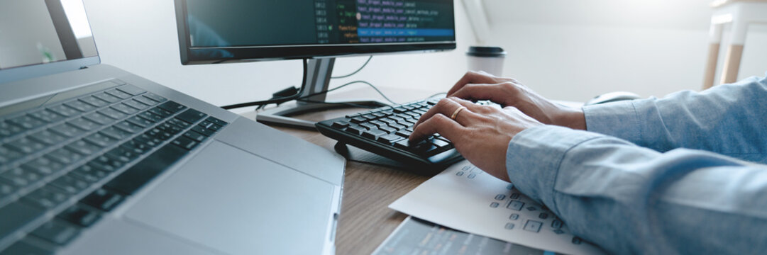 Programmer working On Computer In IT Office Typing Data Coding in software and checking code on computer screen.