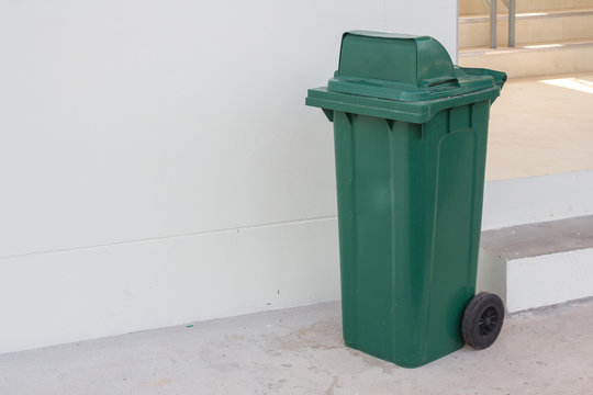 large green wheelie bin for rubbish,Public trash background,Big pile of garbage and waiste in black bags.