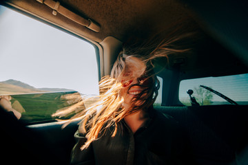 Fototapeta na wymiar redhead girl sitting on back seat of a car and wind waving her hair