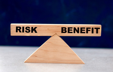 Business balance between risk and profit on wooden scales on a dark background