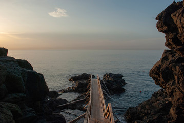 Langer Holzsteg ins Meer an vulkanischer Küste Siziliens, Italien