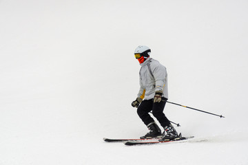 Fototapeta na wymiar Skier goes down the white slope of the mountain