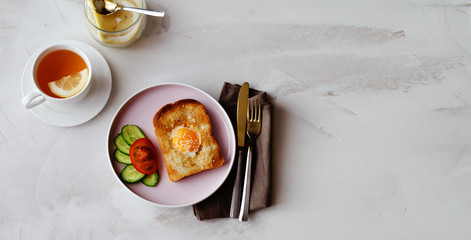 Brunch - an egg with sesame seeds on toast, fresh cucumber and tomato. A cup of tea with lemon. In...