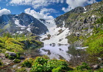 Naklejka na ściany i meble Picturesque mountain lake. Spring in the mountains, snow and flowers.
