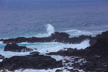 Beautiful Nature scene of sea wave hitting on the black stone shoreline at Jeju Island, South Korea.