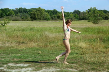 Girl in mini bikini dancing on the river Bank