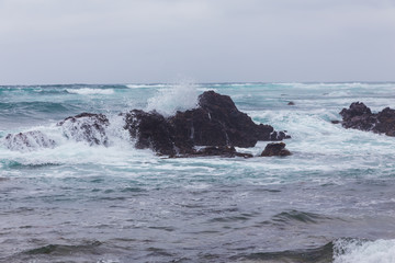 Beautiful Nature scene of sea wave hitting on the black stone shoreline at Jeju Island, South Korea.