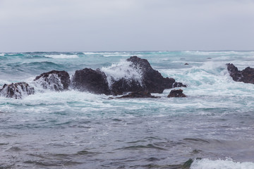 Beautiful Nature scene of sea wave hitting on the black stone shoreline at Jeju Island, South Korea.