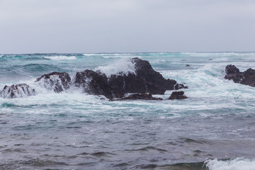 Beautiful Nature scene of sea wave hitting on the black stone shoreline at Jeju Island, South Korea.