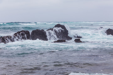 Beautiful Nature scene of sea wave hitting on the black stone shoreline at Jeju Island, South Korea.