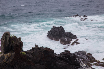 Beautiful Nature scene of sea wave hitting on the black stone shoreline at Jeju Island, South Korea.