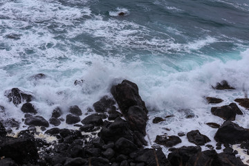 Beautiful Nature scene of sea wave hitting on the black stone shoreline at Jeju Island, South Korea. 