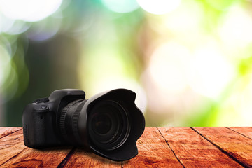 Digital camera on wooden table with blurred on nature bokeh background