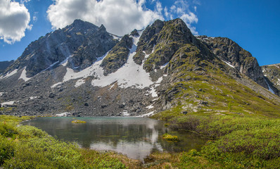 A small mountain lake. Rocky peaks and snowfields. Spring in the mountains.