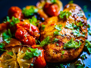 Roast chicken breast and vegetables on wooden background