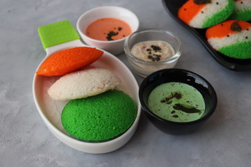 Tiranga Idli or Tricolor Idly cooked in  Indian National Flag colors - saffron or orange, white and green. Served with tiranga chutney. Concept for Indian Independence or Republic day greeting card.