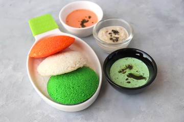 Tiranga Idli or Tricolor Idly cooked in  Indian National Flag colors - saffron or orange, white and green. Served with tiranga chutney. Concept for Indian Independence or Republic day greeting card.