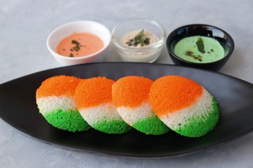 Tiranga Idli or Tricolor Idly cooked in  Indian National Flag colors - saffron or orange, white and green. Served with tiranga chutney. Concept for Indian Independence or Republic day greeting card.