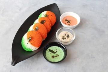 Tiranga Idli or Tricolor Idly cooked in  Indian National Flag colors - saffron or orange, white and green. Served with tiranga chutney. Concept for Indian Independence or Republic day greeting card.