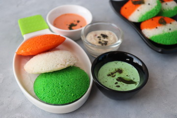Tiranga Idli or Tricolor Idly cooked in  Indian National Flag colors - saffron or orange, white and green. Served with tiranga chutney. Concept for Indian Independence or Republic day greeting card.