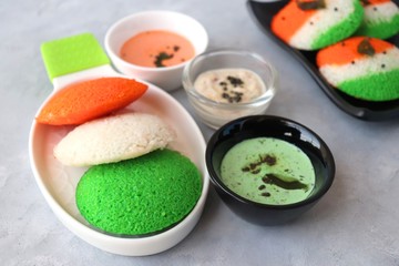 Tiranga Idli or Tricolor Idly cooked in  Indian National Flag colors - saffron or orange, white and green. Served with tiranga chutney. Concept for Indian Independence or Republic day greeting card.