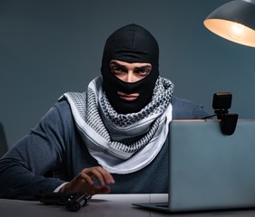 Hacker wearing balaclava mask hacking computer