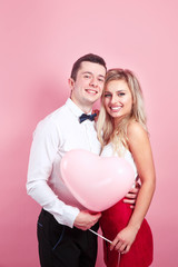 Beautiful romantic couple with pink balloon on studio background