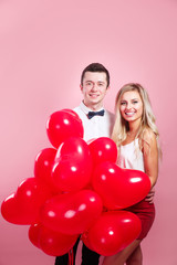 young loving couple with balloons heart on pink background