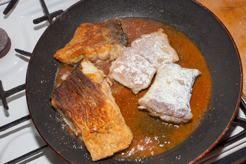 pan with fried fish in tomato sauce and oil.