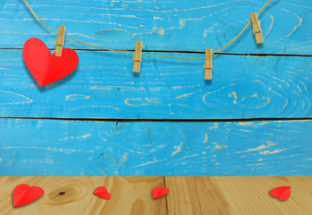 A Valentine's day concept.A red heart shaped card attached to a wooden clip Hanging with hemp rope on wood plate  blue.Valentine's Day background