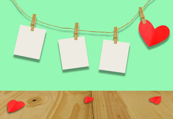 The Valentine's day concept.A red heart shaped card attached to a wooden clip Hanging with hemp rope on pastel  green.Valentine's Day background