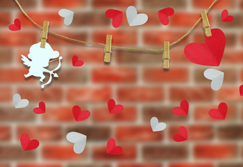 Valentine's day concept.White cupid shaped card attached to a wooden clip Hanging with hemp rope on brick wall .Valentine's Day background