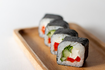 Vegetarian sushi rolls with vegetables on a wooden plate