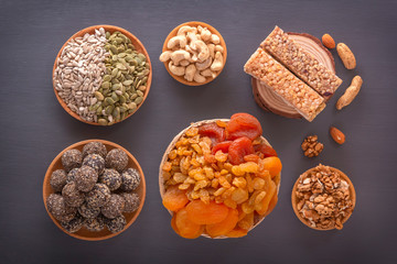 Bars of sports nutrition from nuts, seeds and chocolate paste - vegetable natural protein, a mixture of dried fruits, assorted nuts and seeds on a dark table. Top view