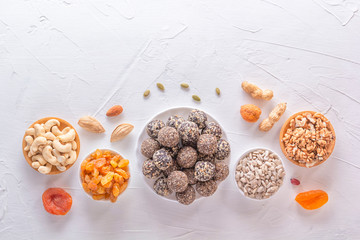 Fototapeta na wymiar Natural healthy raw energy bites and mix of dried fruits with nuts on a white table. Top view. Copy space