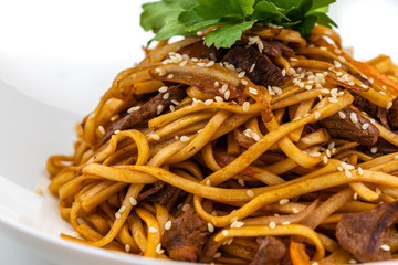 Pan asian food. Wok noodles on a white plate, close up
