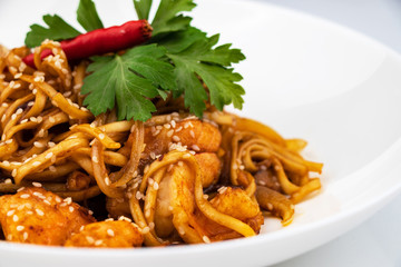 Pan asian food. Wok noodles on a white plate, close up