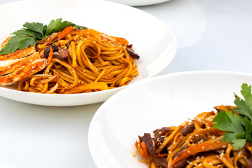 Pan asian food. Wok noodles on a white plate, close up