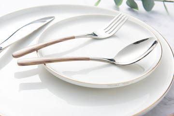 Chopsticks, spoons, knives and forks are arranged on ceramic plates