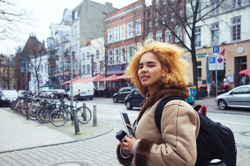 Fototapeta na wymiar young pretty african american girl with curly hair making photo on a tablet, lifestyle people concept, tourist in european german city