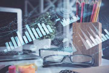Financial chart hologram with glasses on the table background. Concept of business. Double exposure.