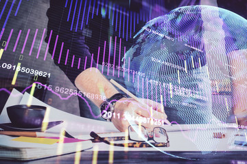Double exposure of man writing on paper with forex graph.